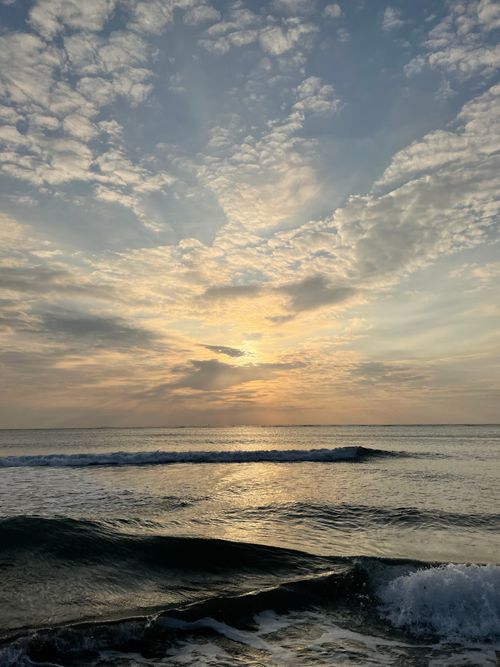 Free A tranquil ocean scene at sunset with gentle waves and a vibrant sky filled with clouds. Stock Photo