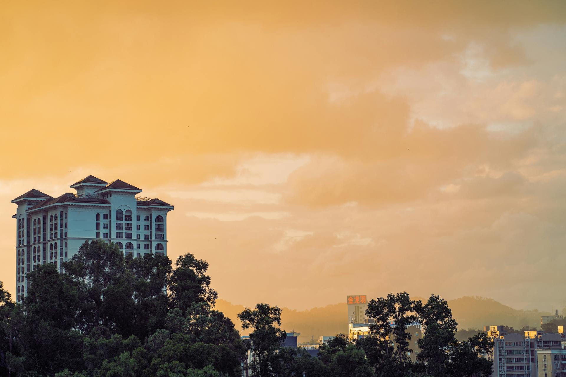 A stunning sunset view over Shenzhen cityscape with dramatic clouds and vibrant orange sky.