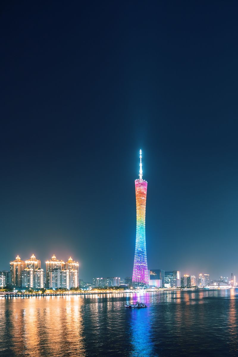 The Canton Tower shifting colors at night, reflected on the Pearl River