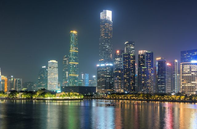 Illuminated skyscrapers of Guangzhou reflecting on the water under a night sky. — arriving in Guangzhou