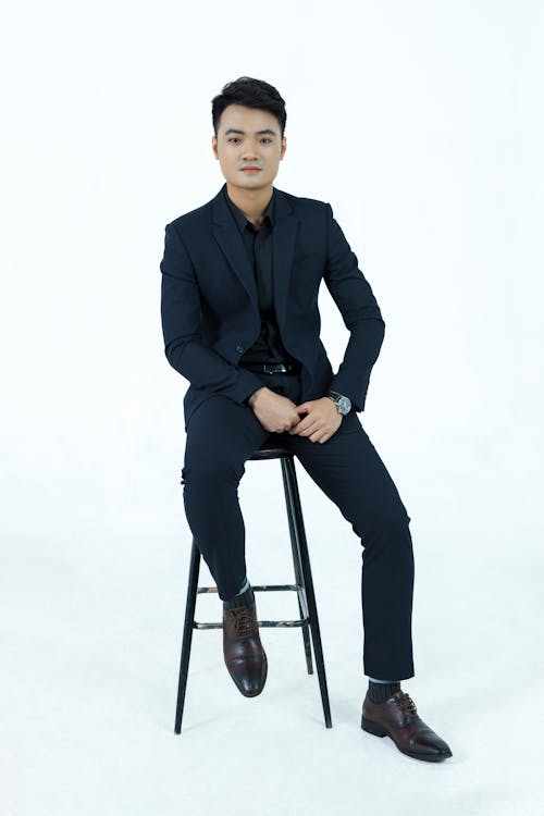 Man in Black Suit Sitting on a Stool