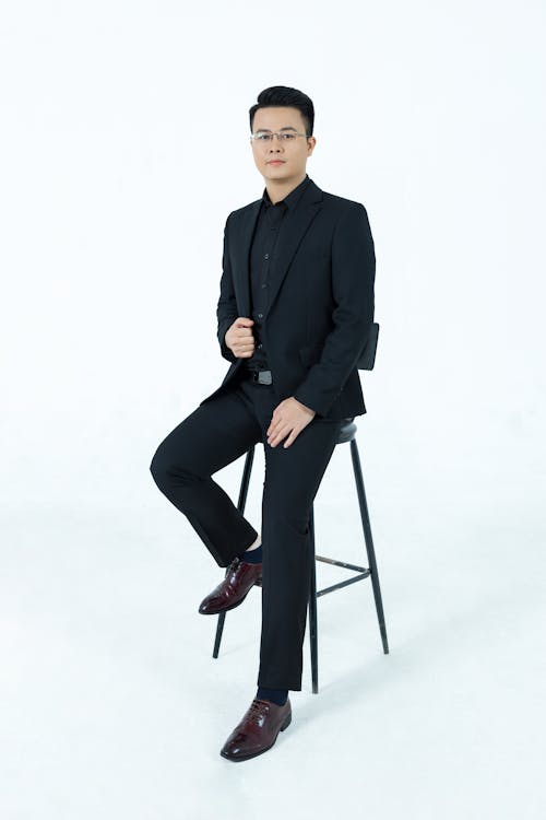 A Man in a Black Suit Sitting on a Chair 