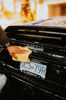 A close-up of a hand cleaning a Lamborghini with a cloth, highlighting luxury car care in Vancouver.