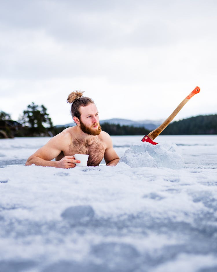 Man Standing In The Frozen River And Holding A Disposable Cup 