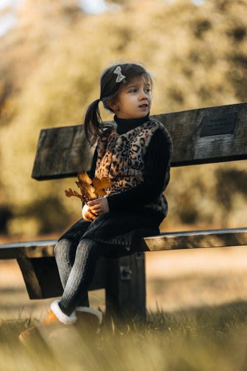 Little Girl Sitting on Wooden Bench