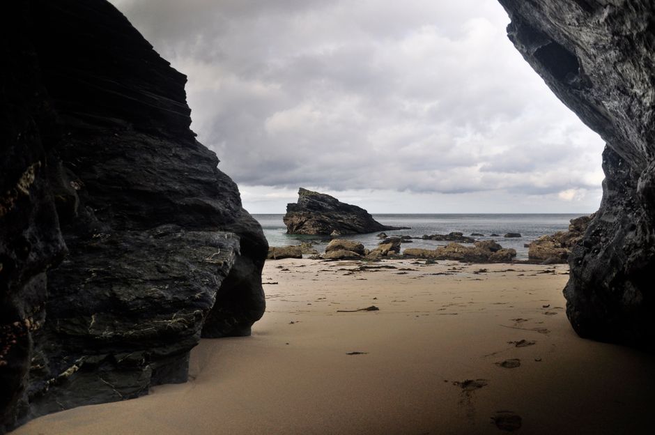 Explore the stunning rocky beach landscape visible from a coastal cave in Camborne, England.