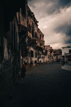 Gloomy urban scene showcasing historic architecture along a cobblestone street under a moody sky.