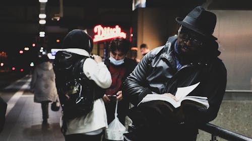 A Man in Black Leather Jacket Reading Book