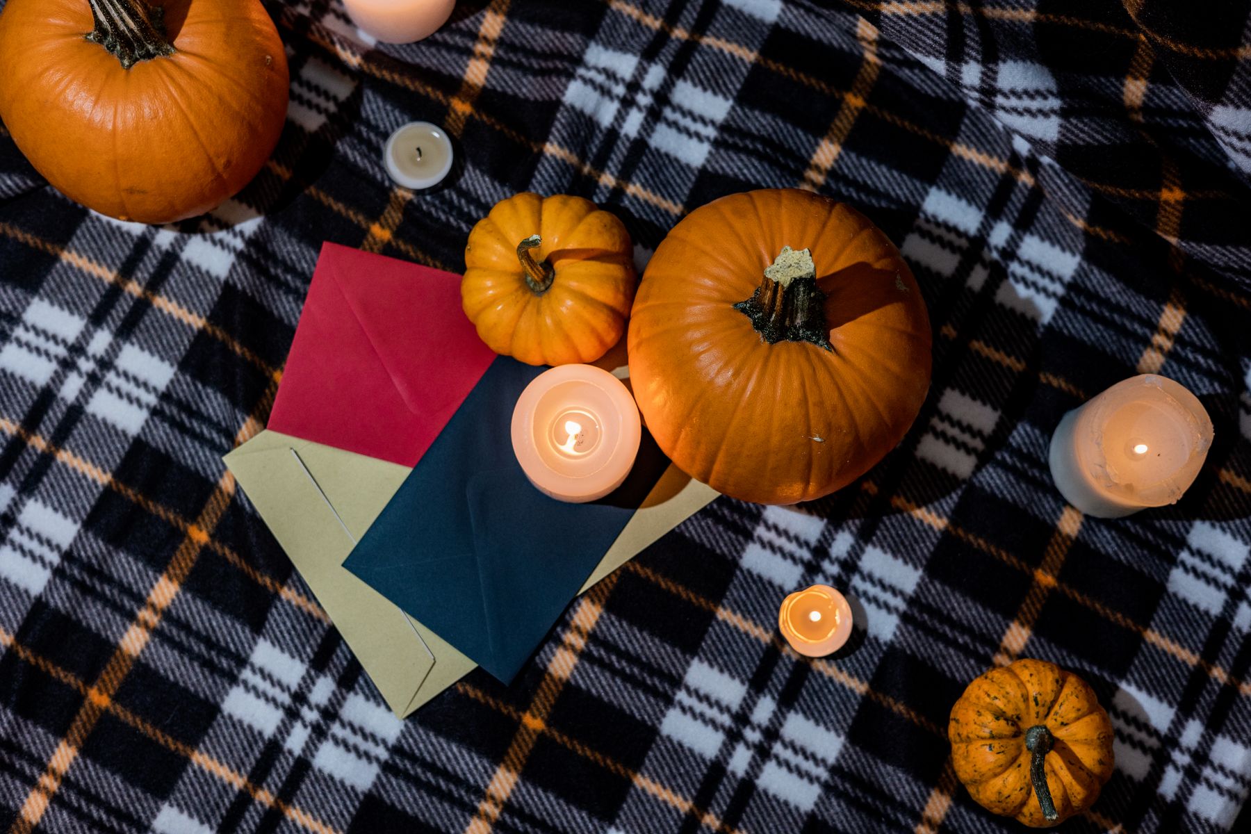 Pumpkins candles and plaid blanket creating a warm fall vignette