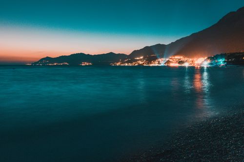 Free Beautiful coastal seascape at dusk with vibrant town lights and serene ocean view. Stock Photo