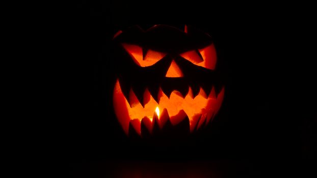 Eerie carved pumpkin glowing with candlelight, perfect for Halloween decor.