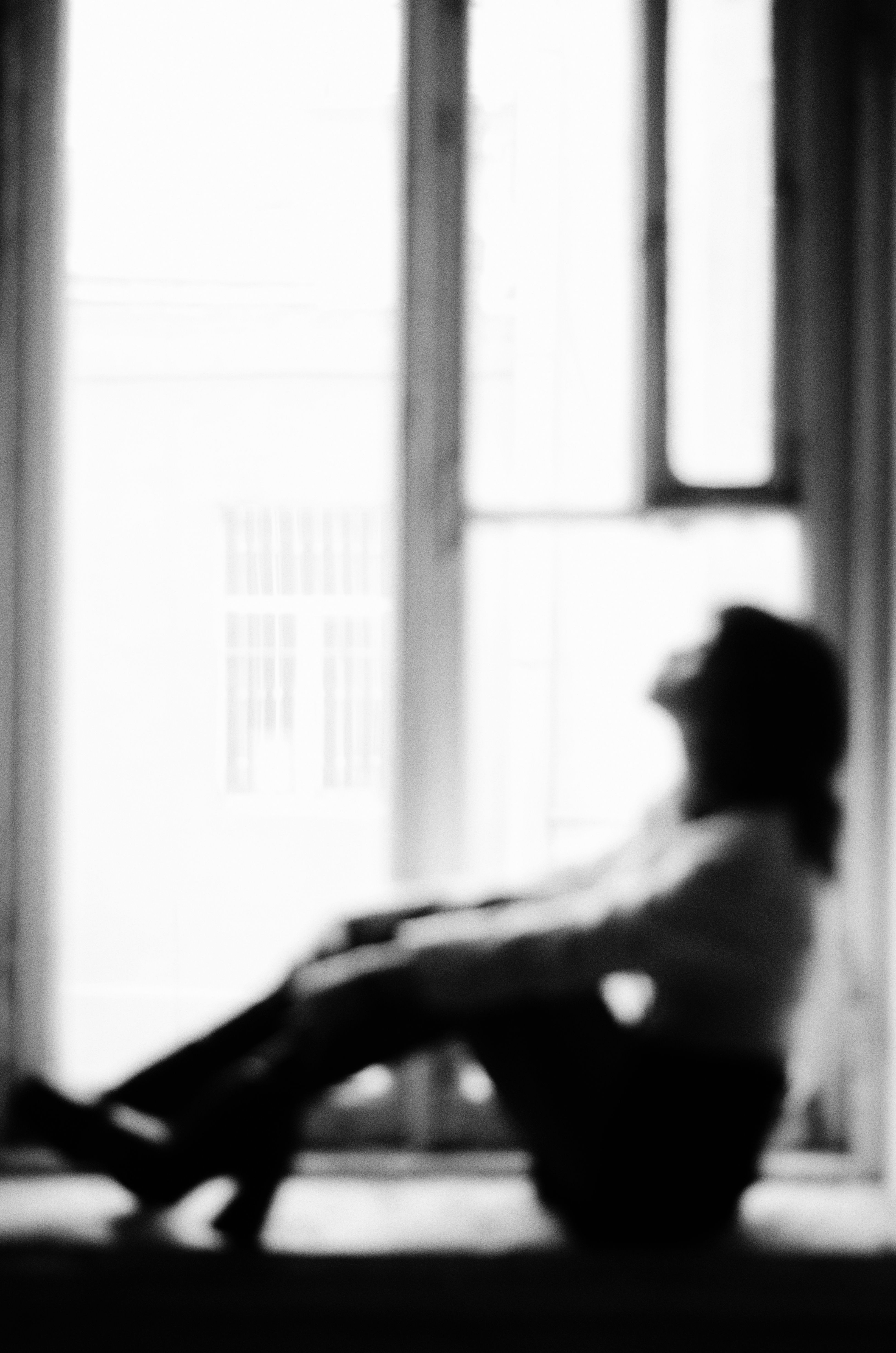 Silhouette of a person sitting in profile against a softly lit window.
