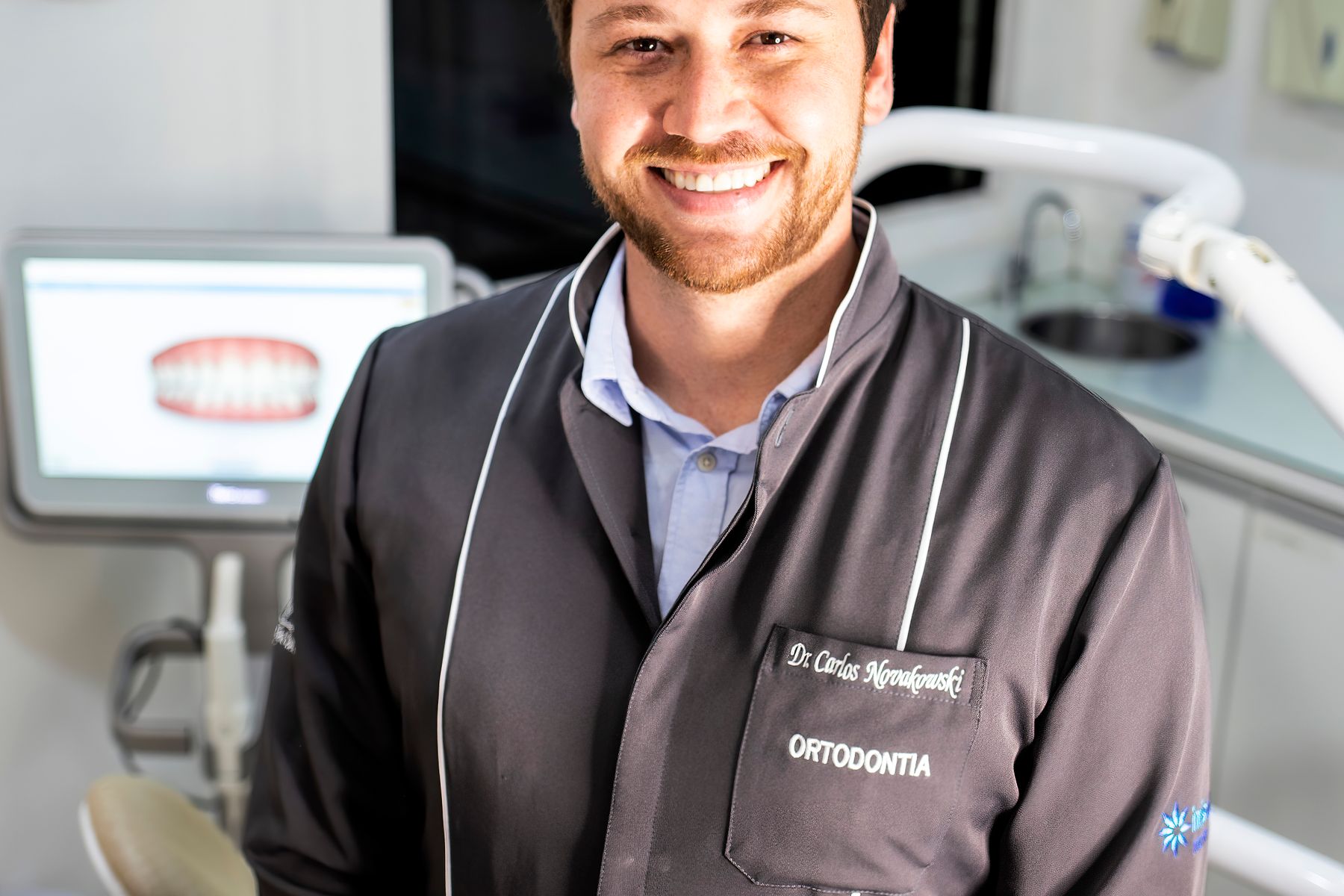 Smiling orthodontist standing in a modern dental clinic