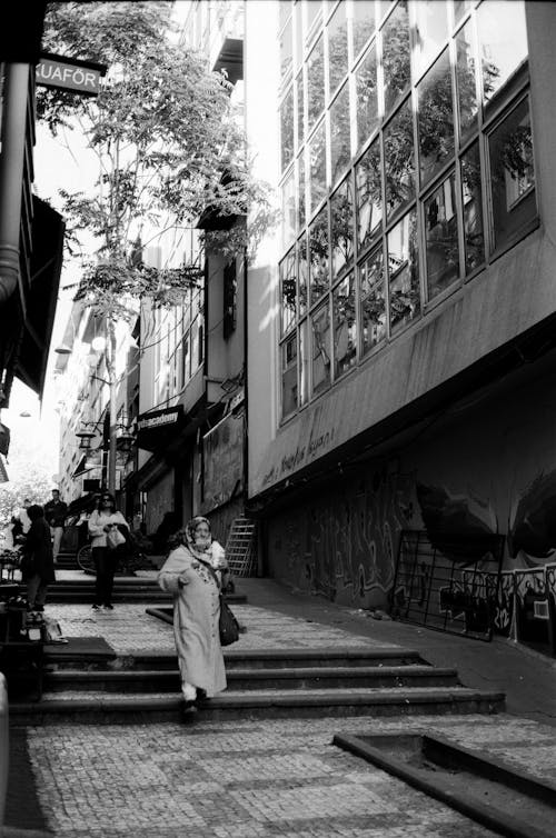 Grayscale Photo of People Walking on Narrow Street