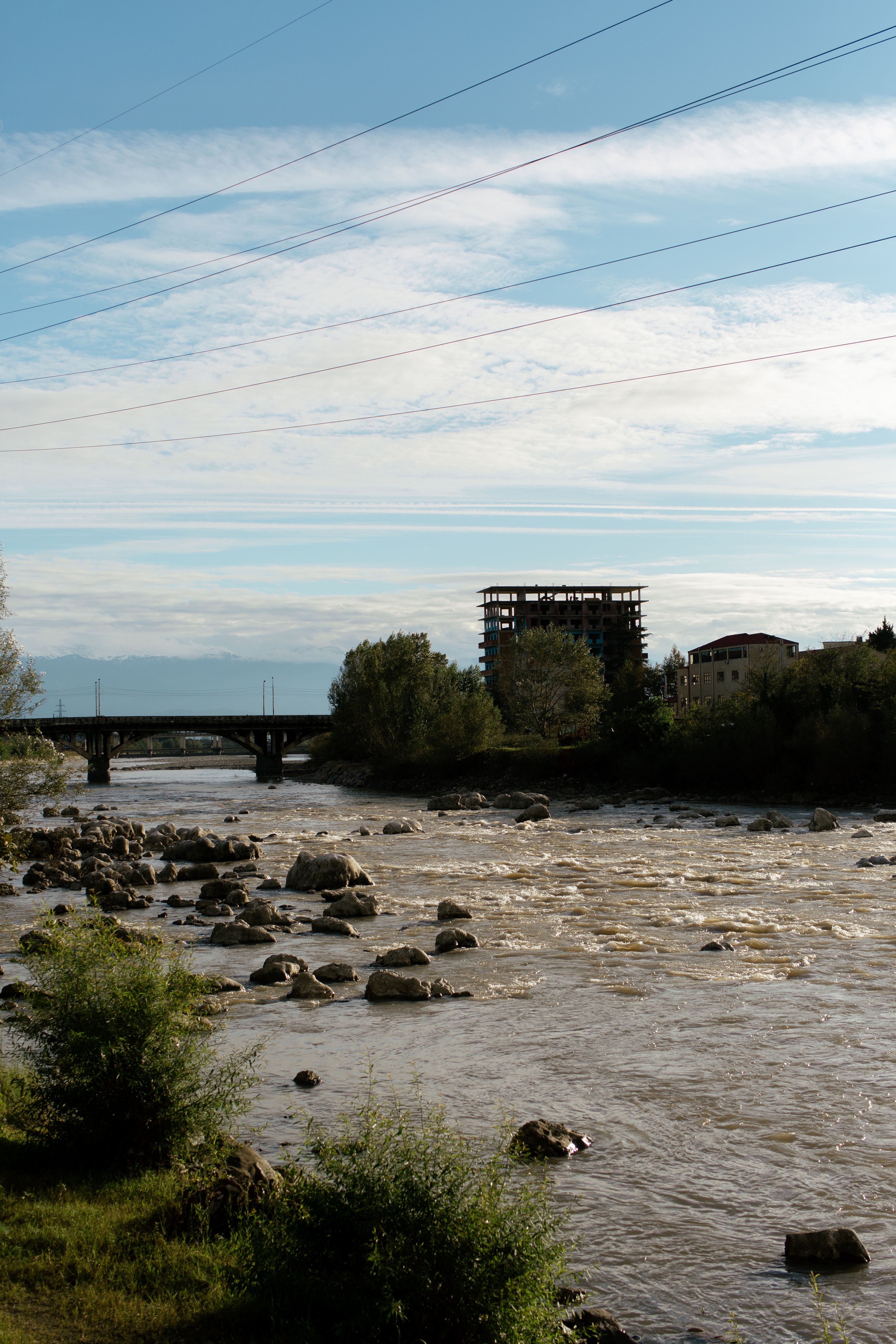 A Rocky River Near the Green Trees Under the Blue Sky and White Clouds ...