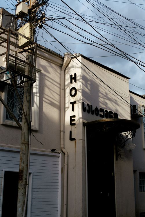 Free A hotel entrance with visible electrical wires and shadows in an urban setting. Stock Photo