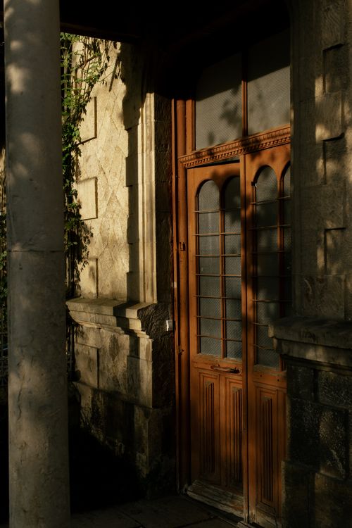 Free Old wooden door with intricate details and natural shadows creating a warm, rustic atmosphere. Stock Photo