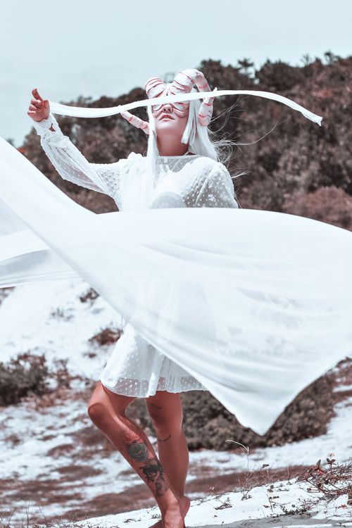 Free A mystical woman with tattoos dances gracefully in a flowing white dress outdoors. Stock Photo