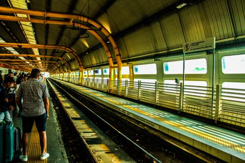Free Commuters waiting at a busy urban train station platform with railway tracks. Stock Photo
