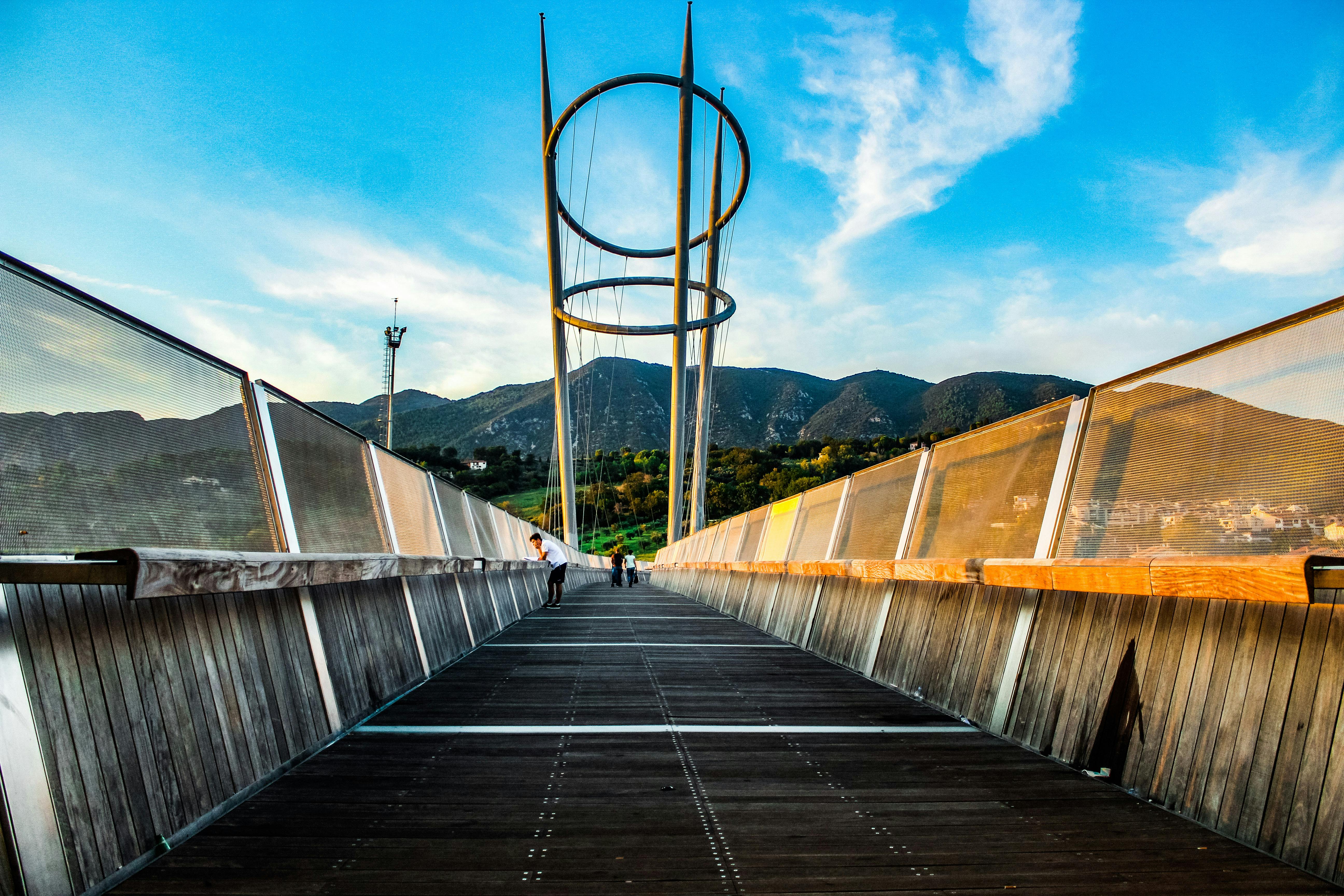 一座设计独特的现代化桥梁，在晴朗的天空下映衬着美丽的山地景观