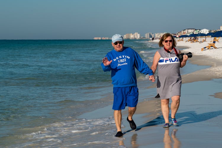 Elderly Couple Holding Hands Walking On Beach