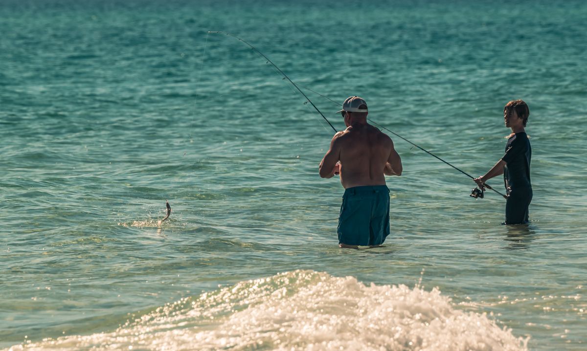 Father and son fishing together in shallow turquoise water