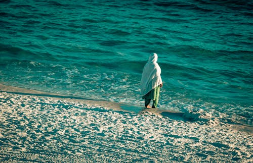 A Woman with Hijab Standing on the Beach Area