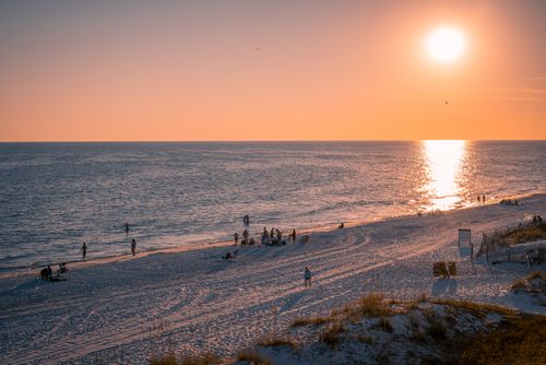 Free A scenic view of people enjoying a beach sunset with calm ocean reflections. Stock Photo