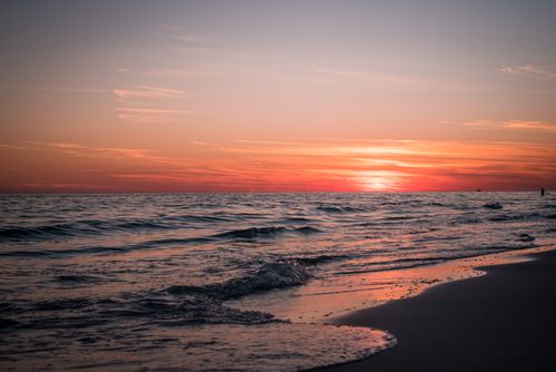 Free Serene ocean waves under a glowing sunset, creating a picturesque seascape at the beach. Stock Photo