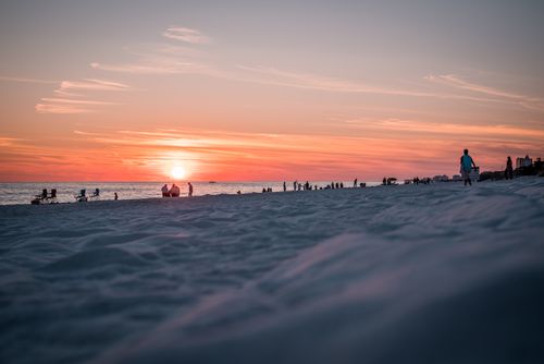 Free Silhouettes of people enjoying a vibrant sunset on a sandy beach. Stock Photo