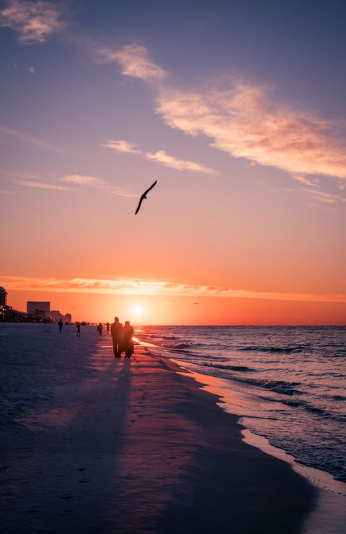 Free Couple walking on beach at sunset, creating romantic and serene atmosphere. Stock Photo