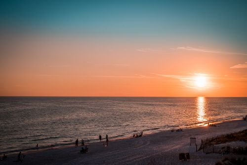 Free Captivating sunset over a serene beach, highlighting people enjoying the tranquil evening vibes. Stock Photo