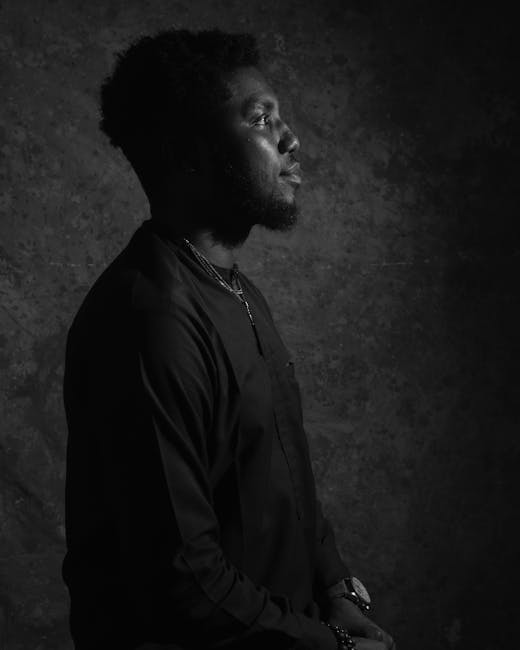 A sophisticated black and white portrait of a man in a side view pose indoors.