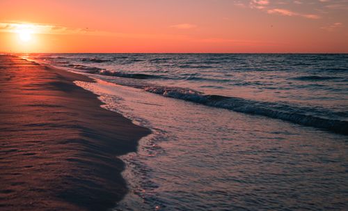 Free Peaceful beach scene with sunset over ocean waves, embodying tranquility and natural beauty. Stock Photo