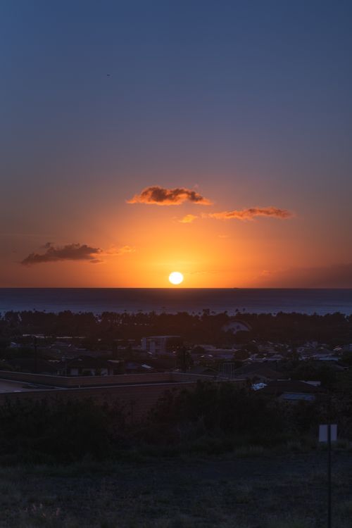 Free Stunning sunset view over an ocean horizon with vibrant colors and silhouetted townscape. Stock Photo