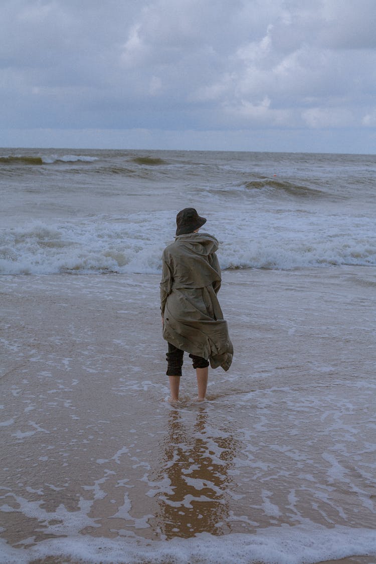 Person In Long Coat Standing On Beach