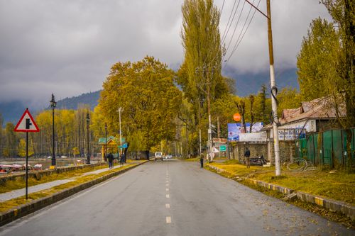 Free Quiet road in Kashmir during autumn, showcasing vibrant fall foliage and distant mountains. Stock Photo