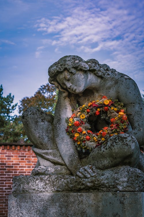 Stone Statue with Flowers in Cemetery