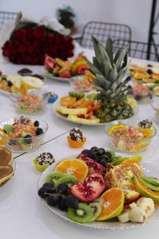 Vibrant fruit arrangement with kiwi, oranges, pomegranate, and sweets on a table.