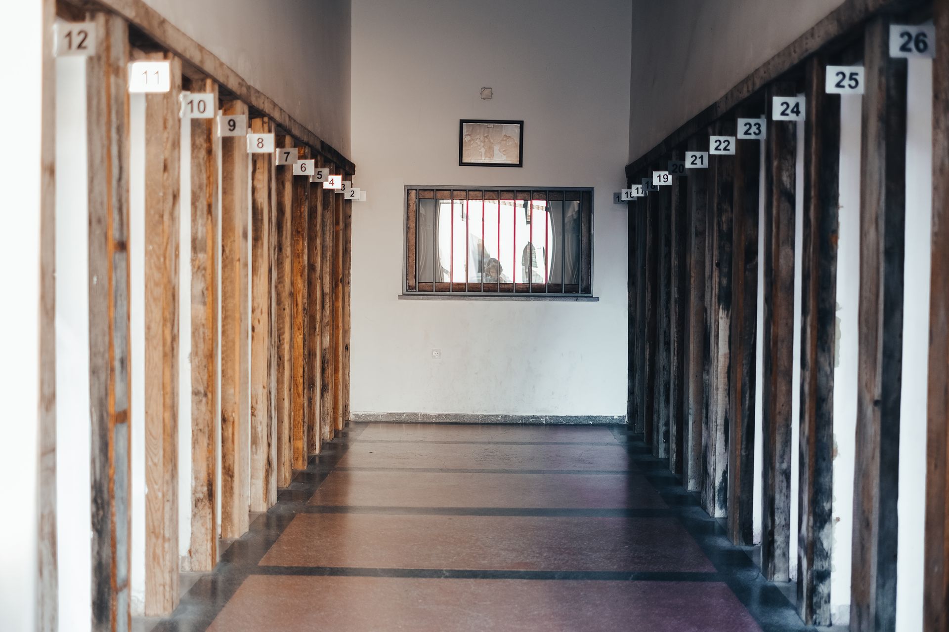 A corridor with wooden walls numbered and a window at the end, photographed indoors.