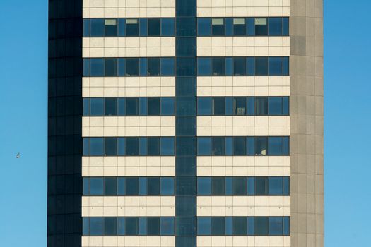 Close-up of a modern skyscraper facade featuring symmetrical windows and clear blue sky.