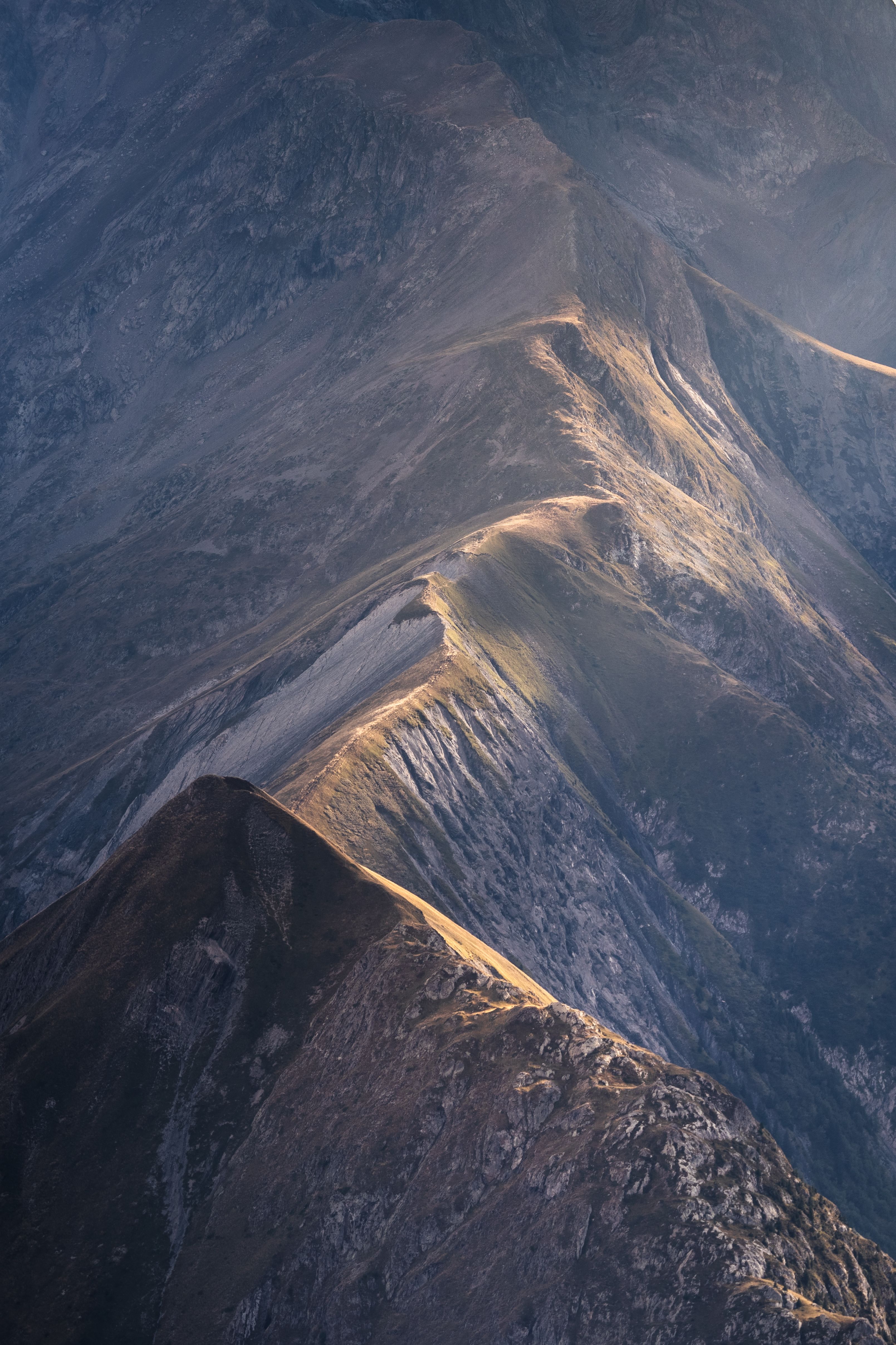 Stunning aerial view of a rugged mountain range captured during golden hour with dramatic sunlight.