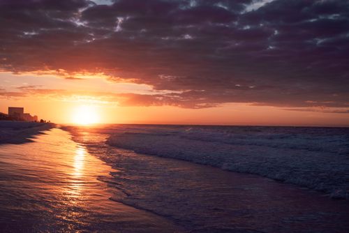 Free Stunning beach sunset with vibrant waves and a colorful sky. Stock Photo
