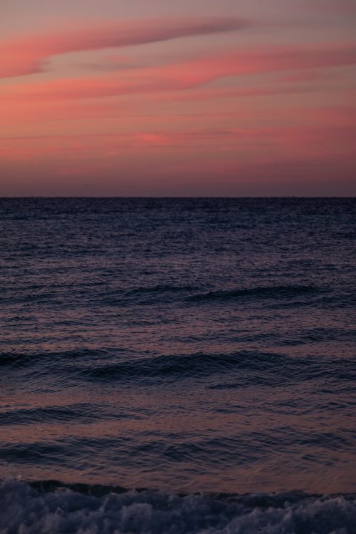 Free Peaceful ocean view at sunset with a pink sky and gentle waves in a vertical orientation. Stock Photo