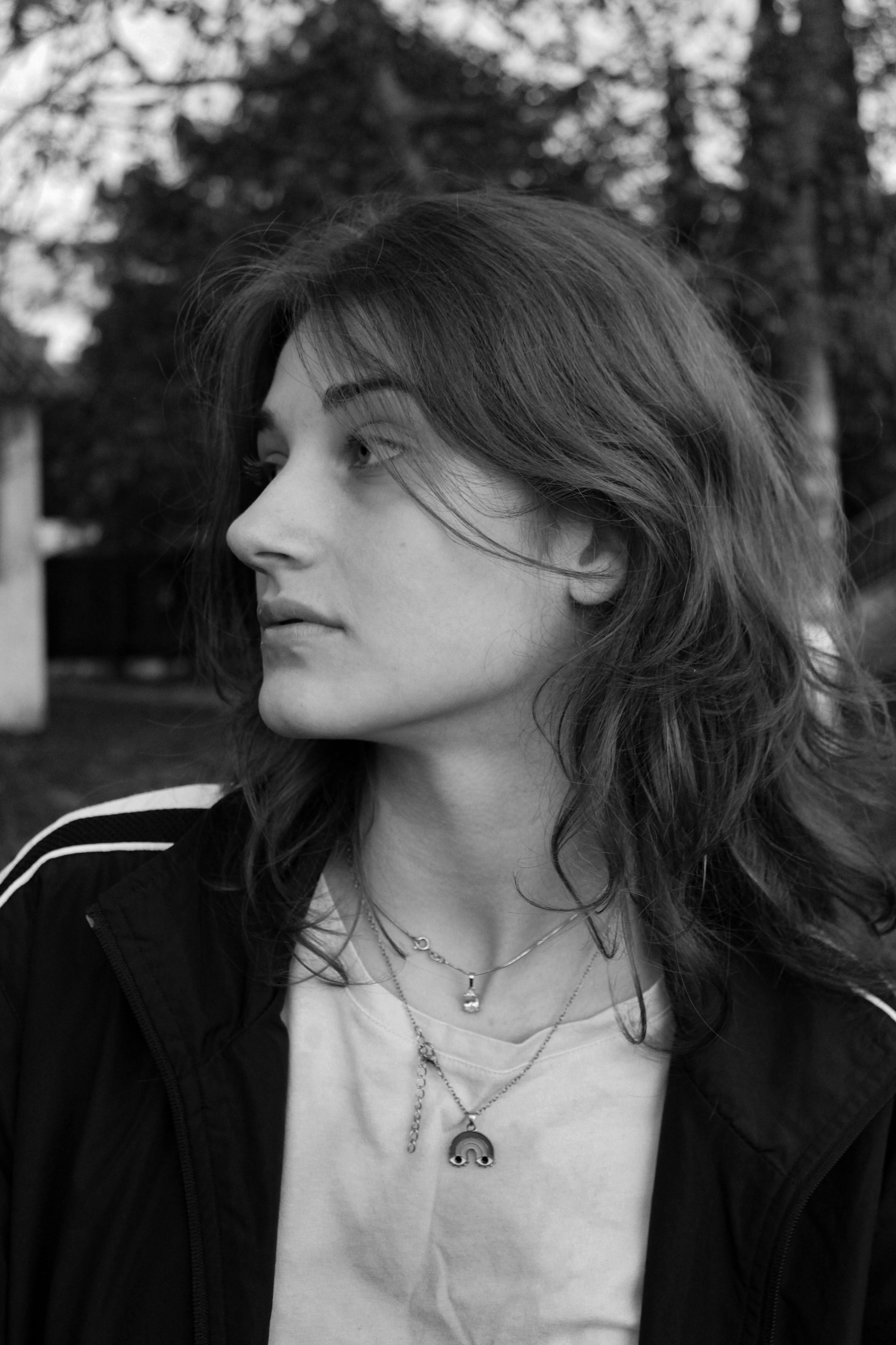 Black and white portrait showcasing a young woman outdoors, highlighting natural beauty and introspective mood.