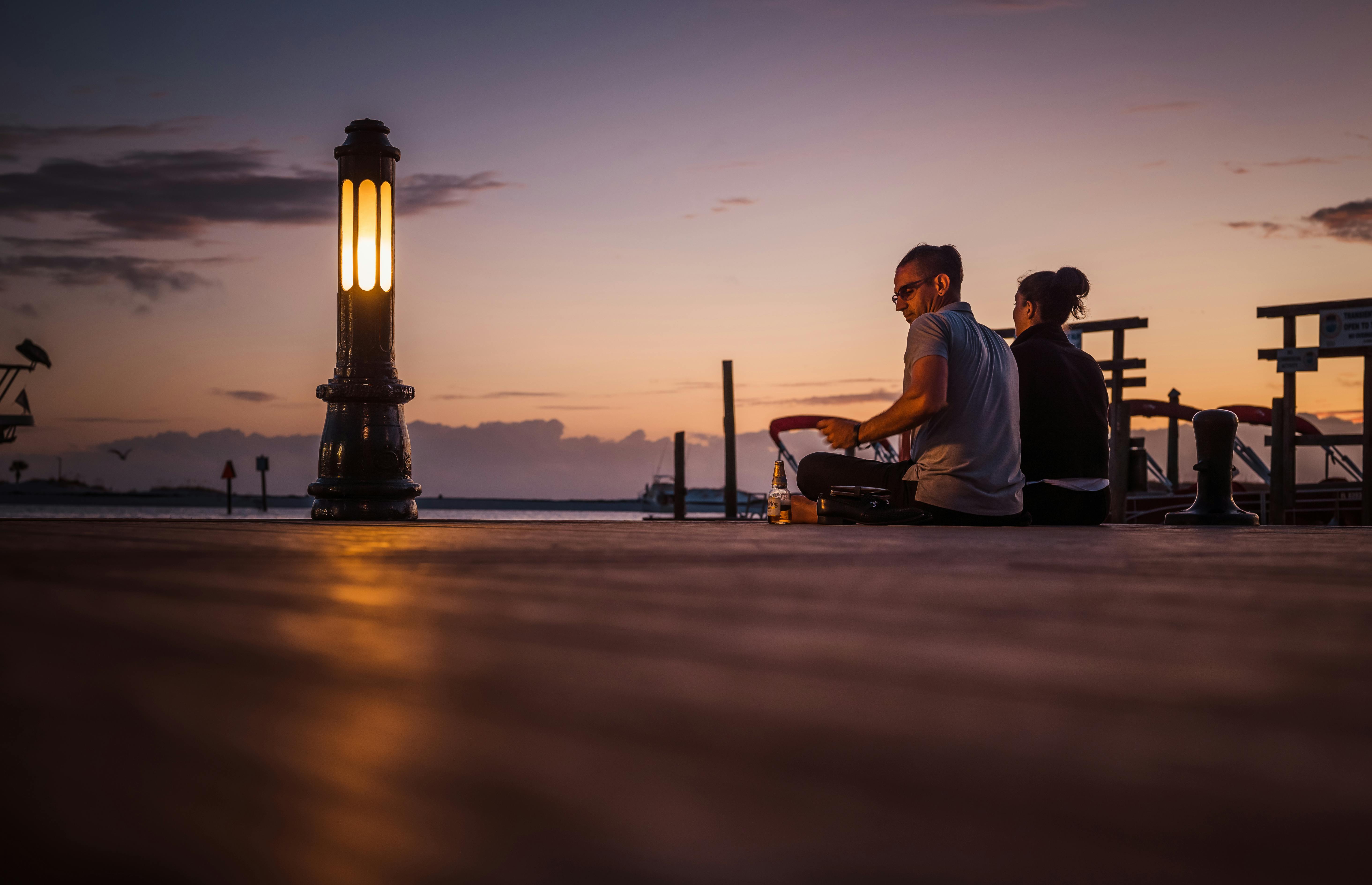 A couple walking along a harbor at sunset