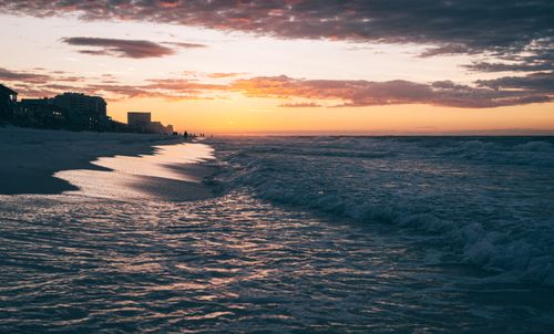 Free Stunning beach scene with crashing waves under a vibrant sunset sky. Stock Photo