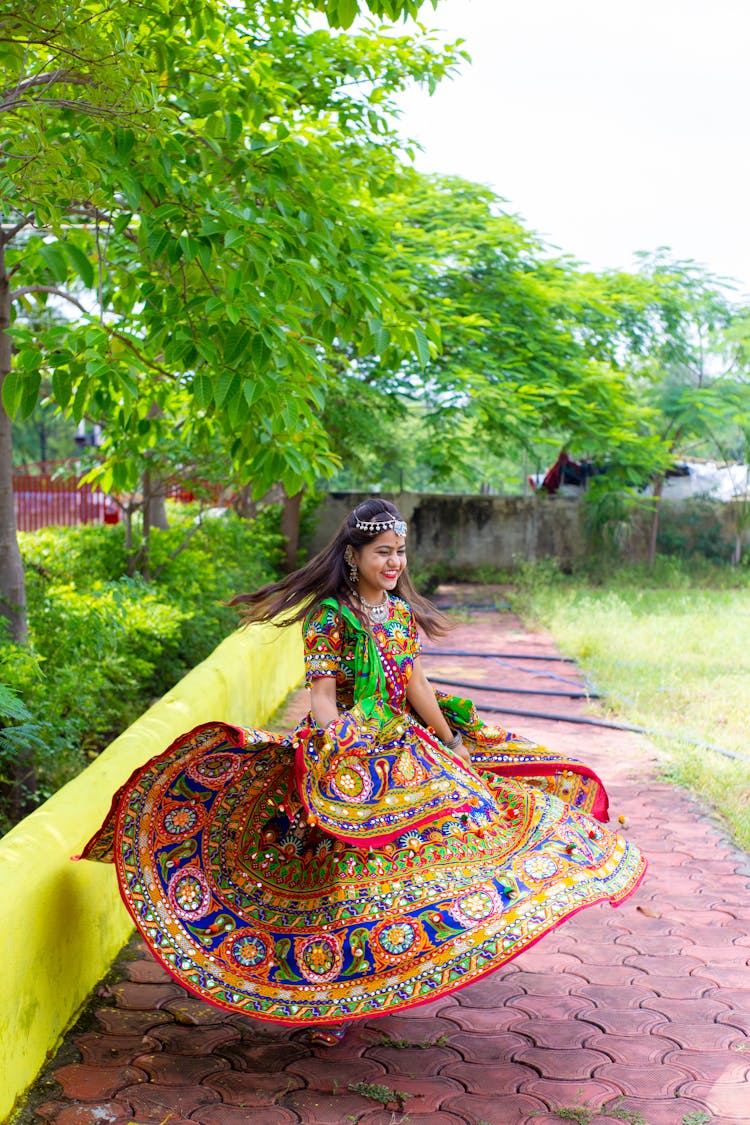 Woman In Printed Dress Dancing Beside A Plant Box