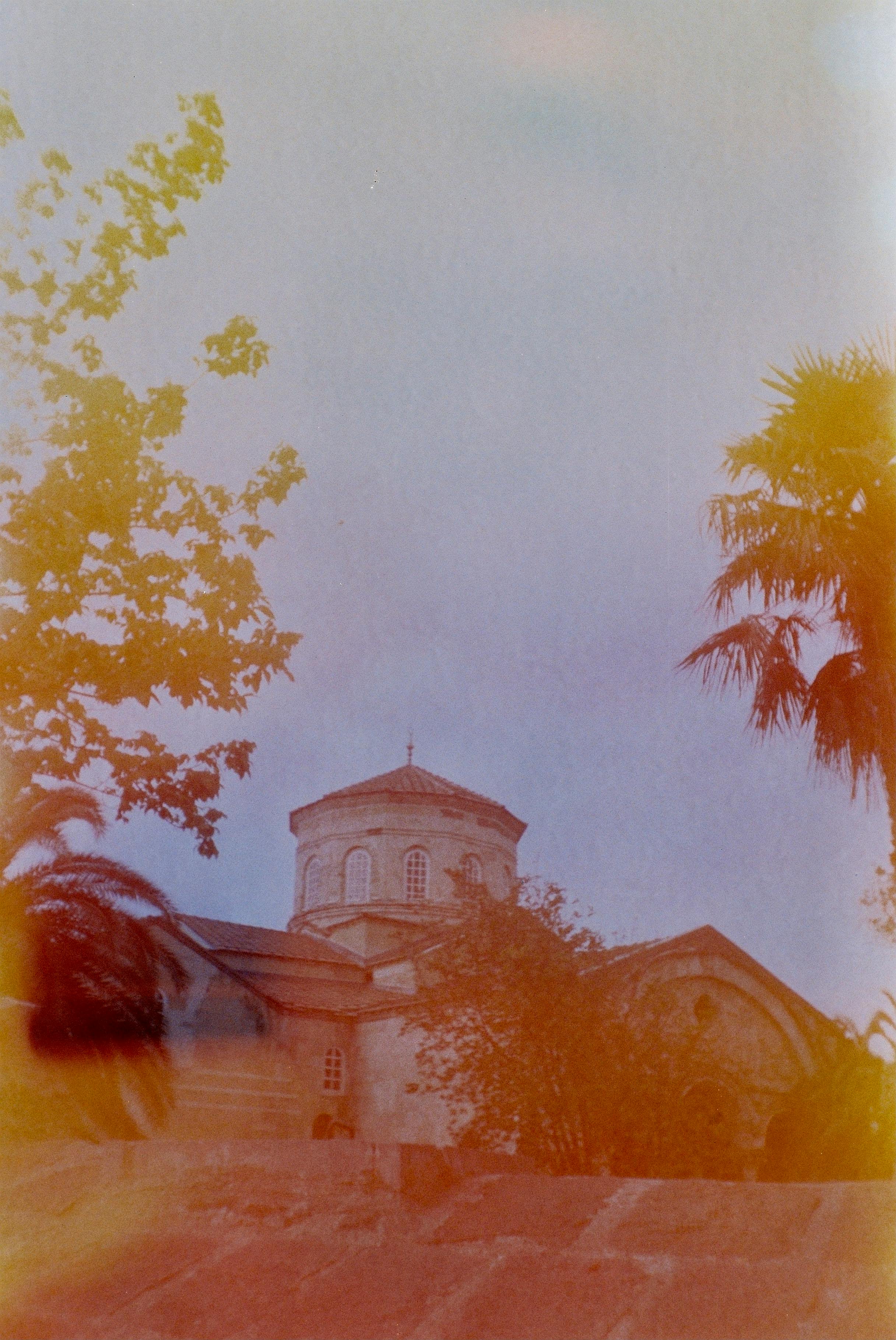 Analog shot of Trabzon's Hagia Sophia, enveloped in trees with an artistic film burn effect.