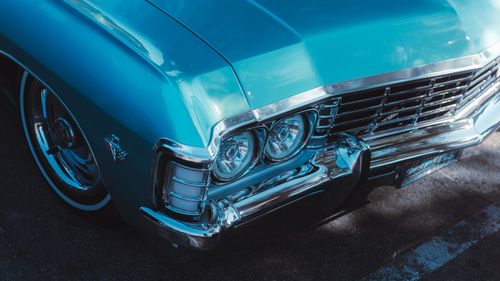 Free Detailed close-up of a classic blue vintage car front with chrome details in sunlight. Stock Photo